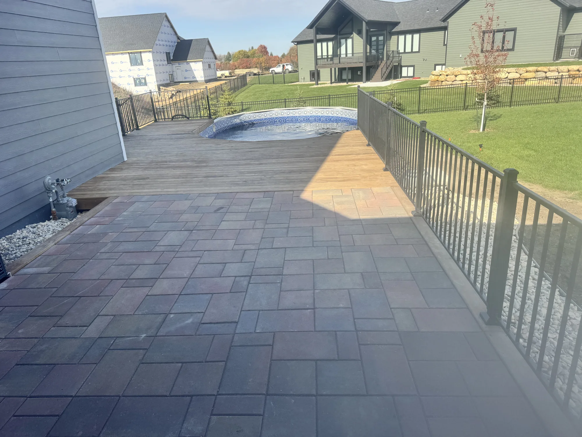 Paver patio beside a pool and deck